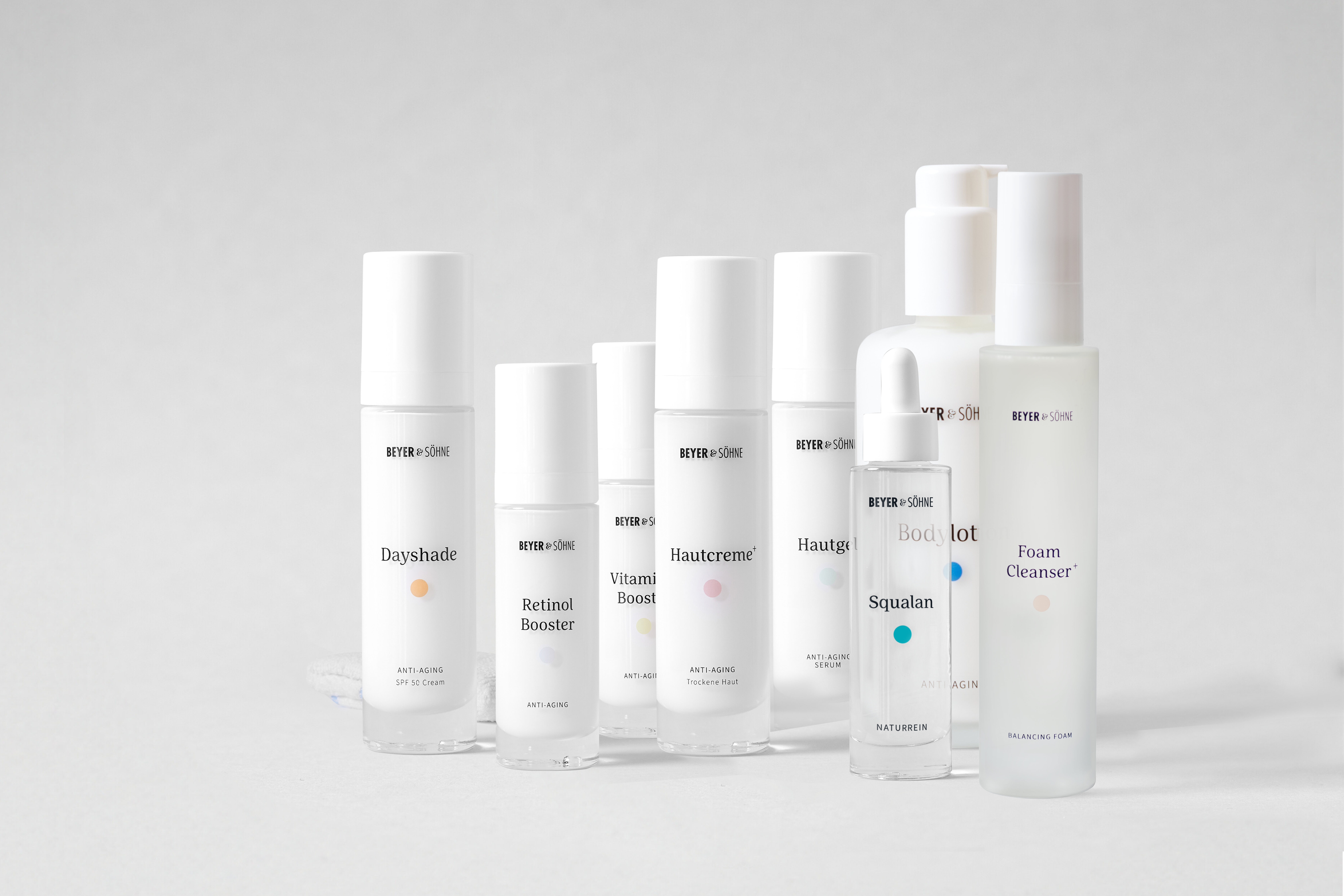 Produktlinie von Beyer & Söhne: Anti-Aging-Pflegeprodukte in minimalistischem Design. Abgebildet sind die Dayshade SPF 50, Retinol Booster, Vitamin C Booster, Hautcreme+ für trockene Haut, Hautgel, Foam Cleanser+, Bodylotion+ und Squalan. Alle Produkte sind dermatologisch getestet, frei von Duftstoffen und speziell für empfindliche Haut geeignet. Perfekt für eine effektive und nachhaltige Pflegeroutine.