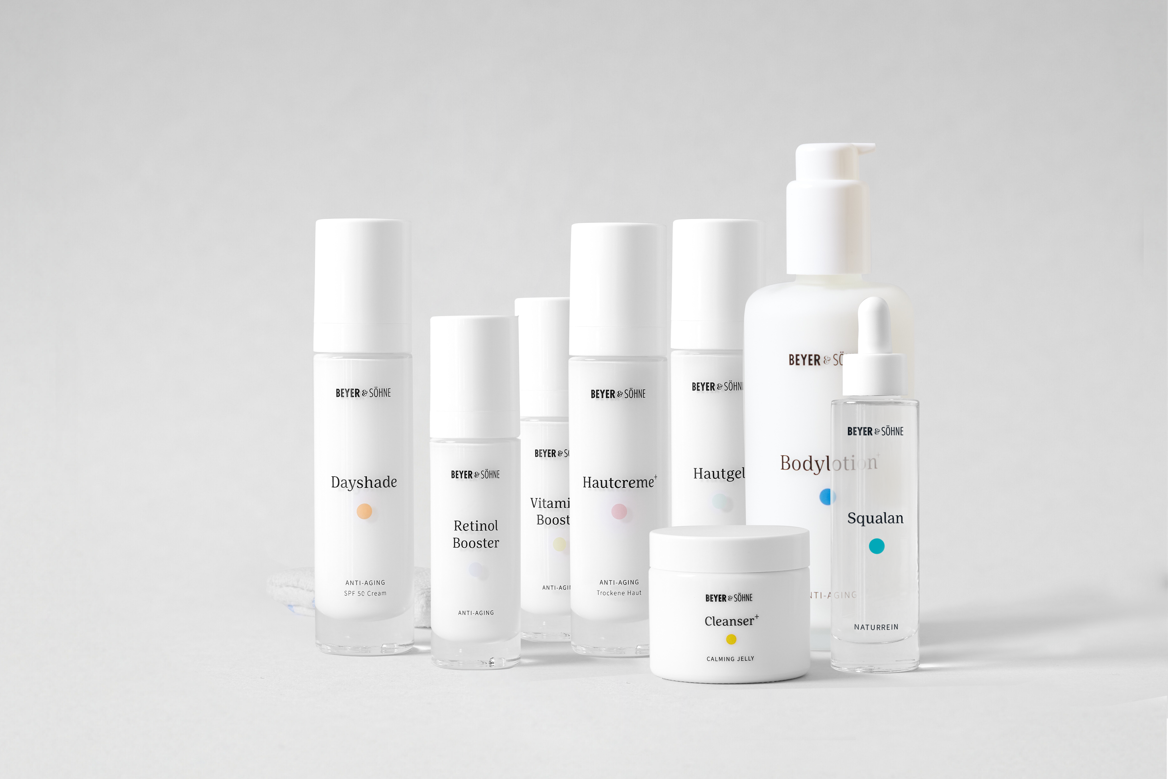 Produktlinie von Beyer & Söhne: Anti-Aging-Pflegeprodukte in minimalistischem Design. Abgebildet sind die Dayshade SPF 50, Retinol Booster, Vitamin C Booster, Hautcreme+ für trockene Haut, Hautgel, Cleanser+, Bodylotion+ und Squalan. Alle Produkte sind dermatologisch getestet, frei von Duftstoffen und speziell für empfindliche Haut geeignet. Perfekt für eine effektive und nachhaltige Pflegeroutine.