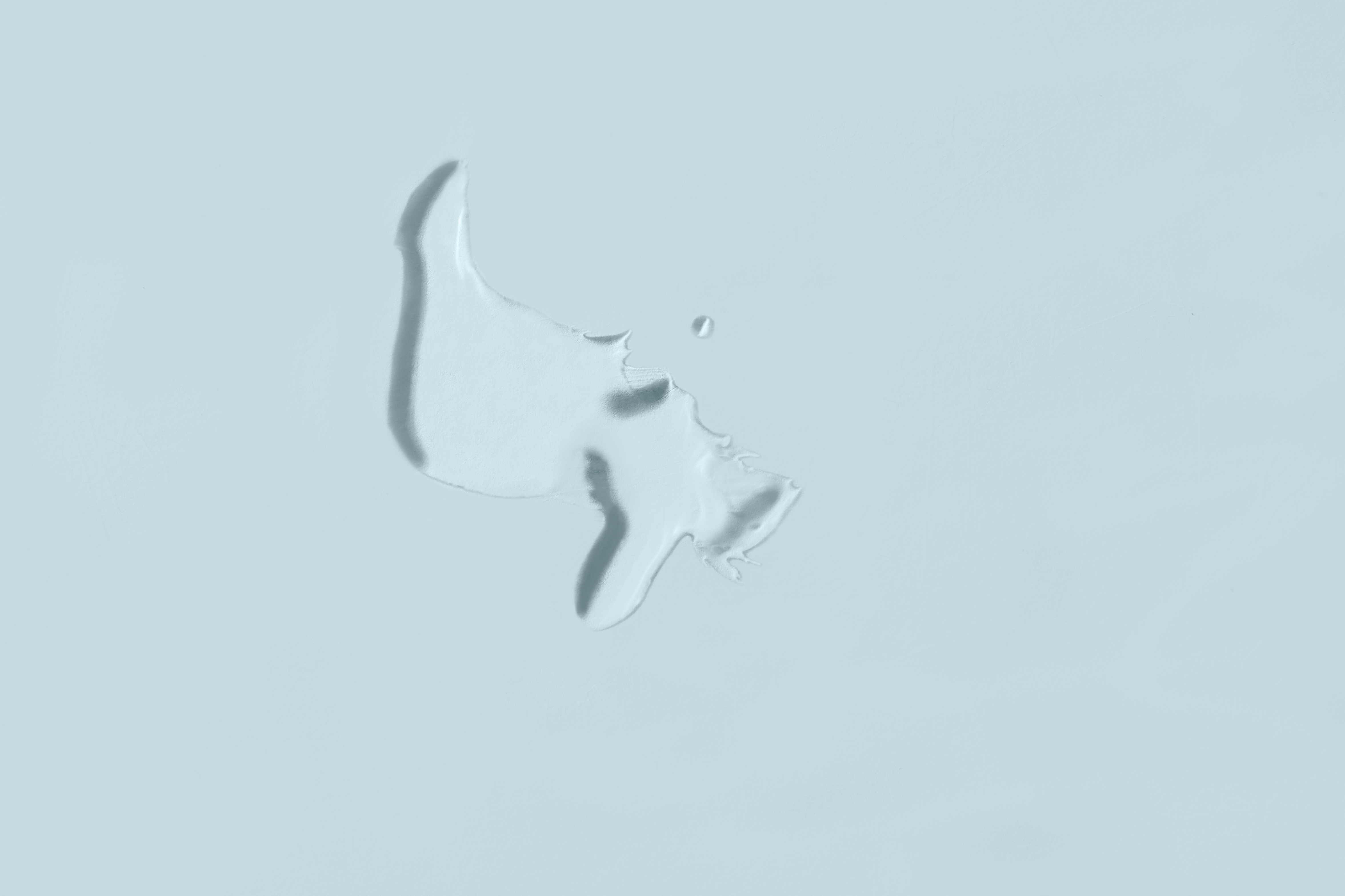 Klecks eines transparenten, wässrigen Fluids auf graublauem Hintergrund