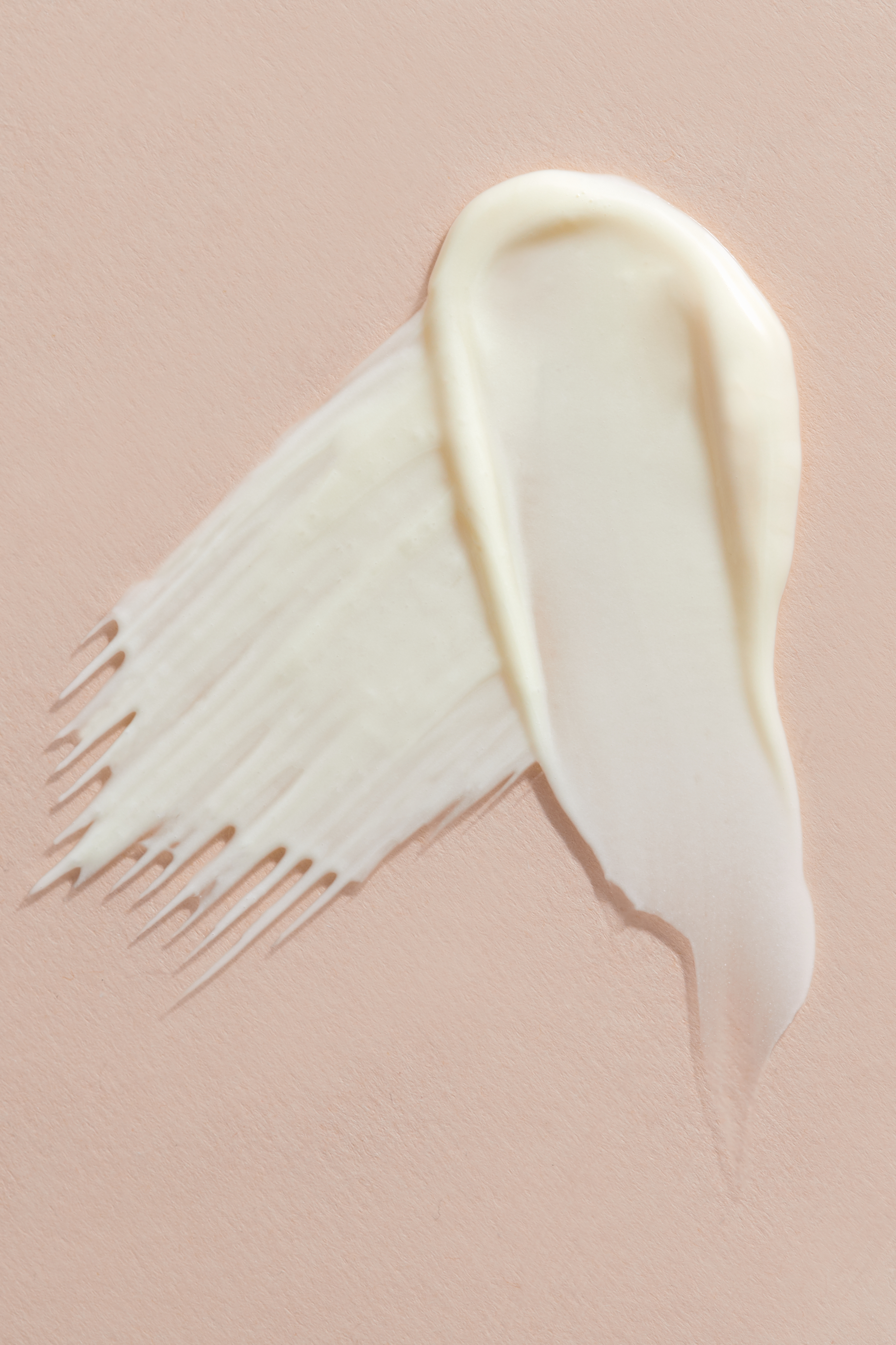 Verwischter Cremeklecks mit leichter gelblicher Färbung auf rosa Hintergrund