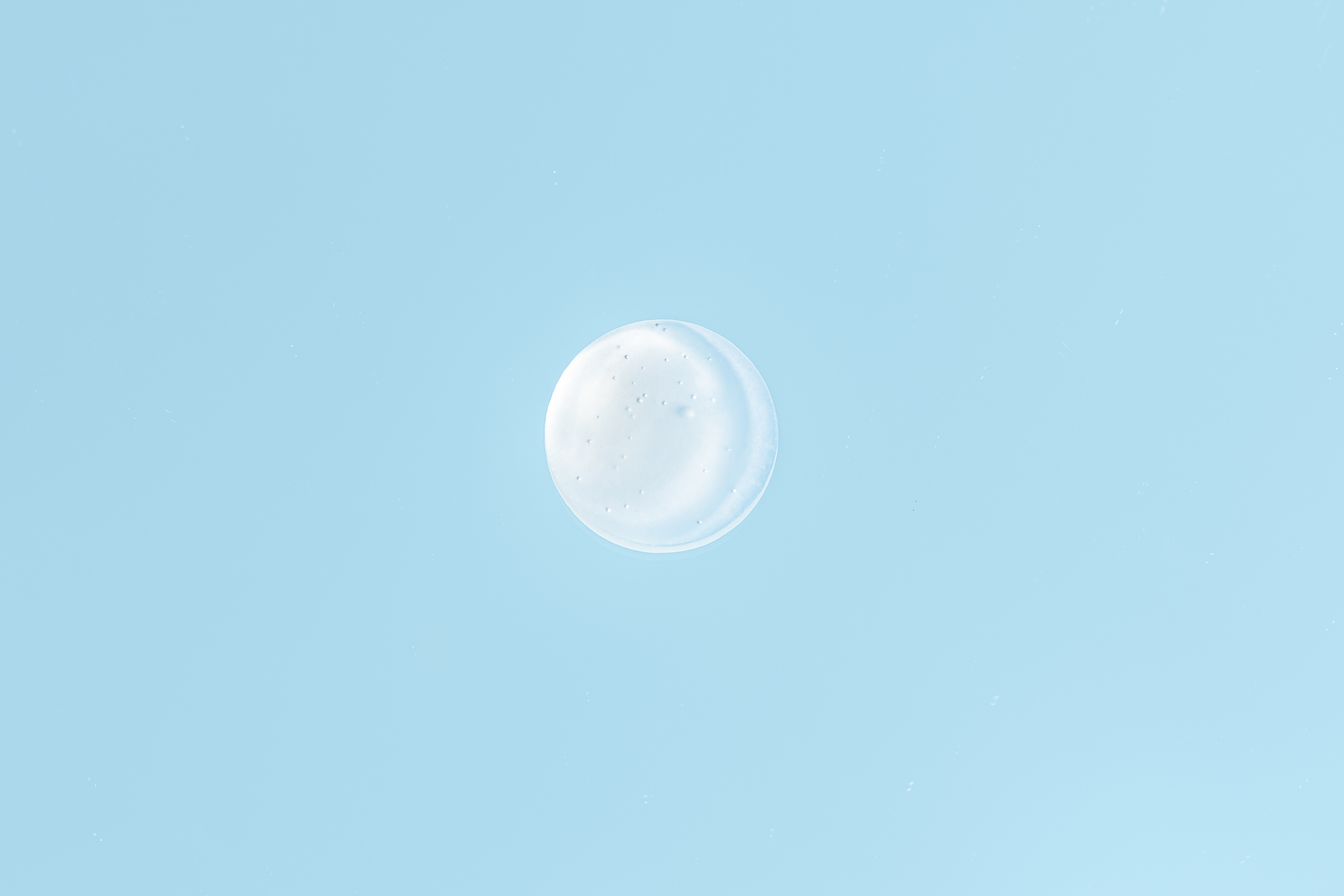 Kleiner Klecks einer weiß-transparenten Gel-Creme auf hellblauem Hintergrund. Die glatte, leichte Textur vermittelt Frische und intensive Feuchtigkeitsversorgung.