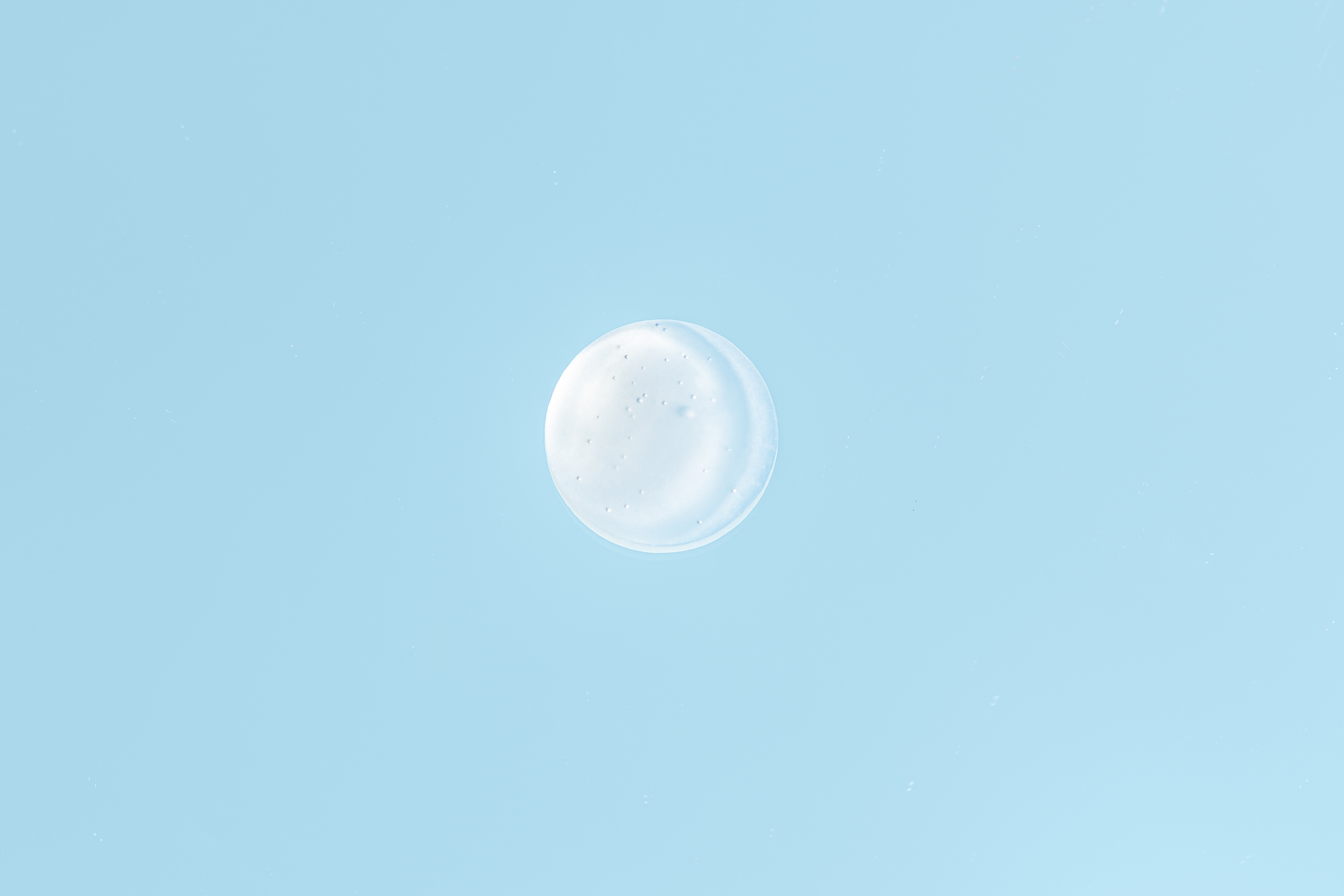 Kleiner Klecks einer weiß-transparenten Gel-Creme auf hellblauem Hintergrund. Die glatte, leichte Textur vermittelt Frische und intensive Feuchtigkeitsversorgung.