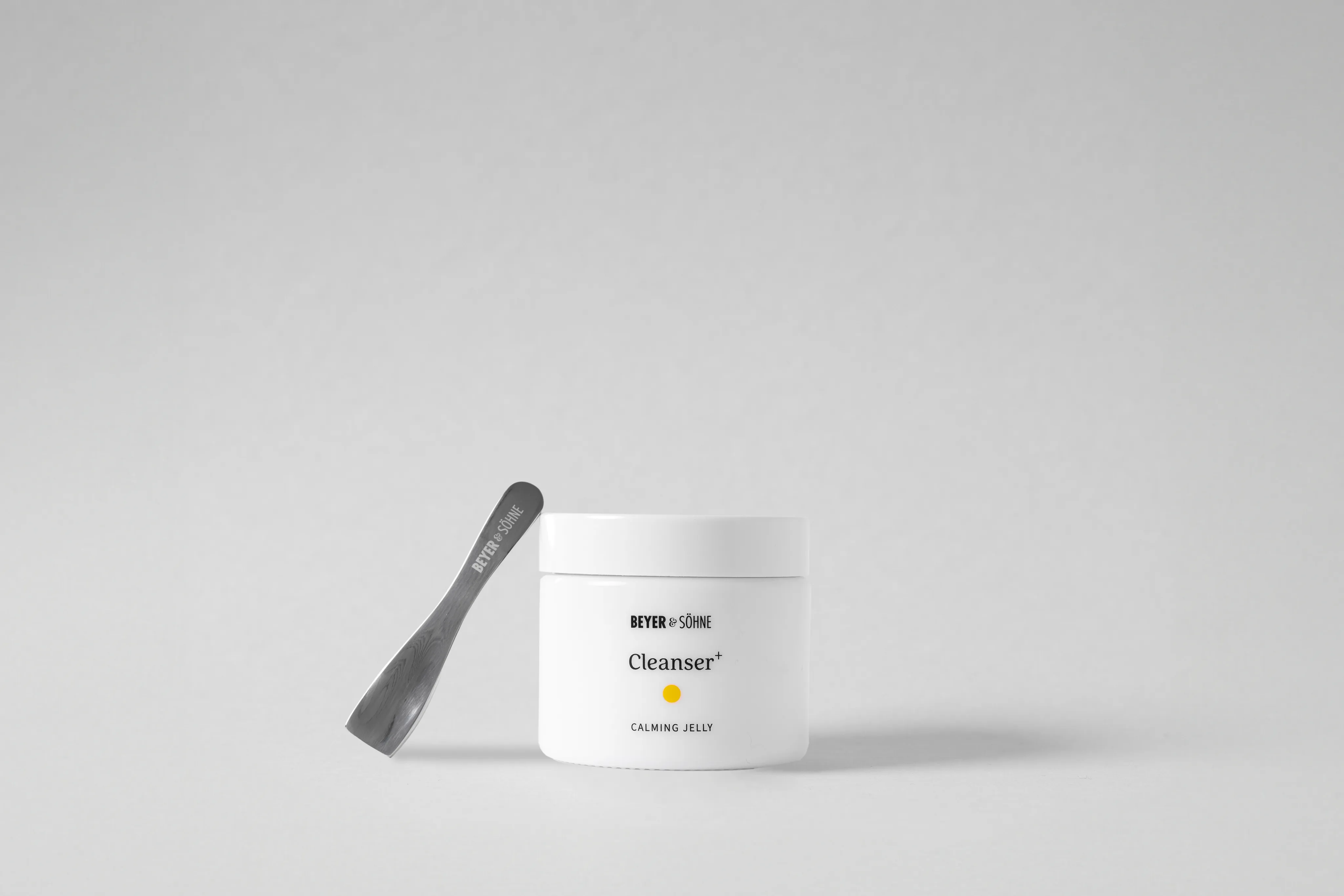 Edler schlichter weißer Tiegel in 50ml Größe und der Aufschrift Beyer&Söhne Cleanser+ Anti-Aging und einem kleinen Edelstahl-Spatel, der am Tiegel anlehnt