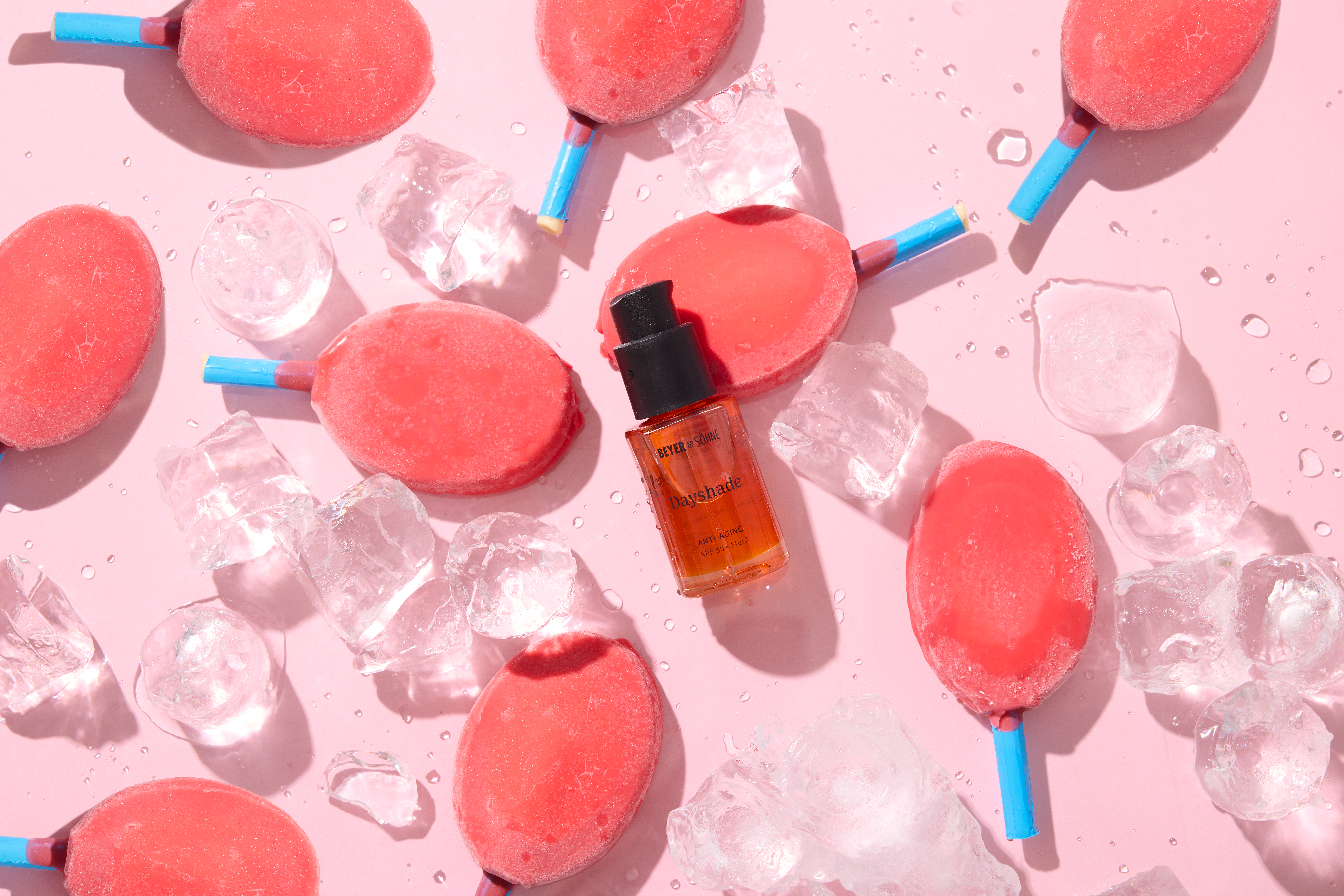 Rotes Dayshade Fluid von Beyer & Söhne mit SPF 50+ zwischen Bum Bum Eis auf rosa Hintergrund