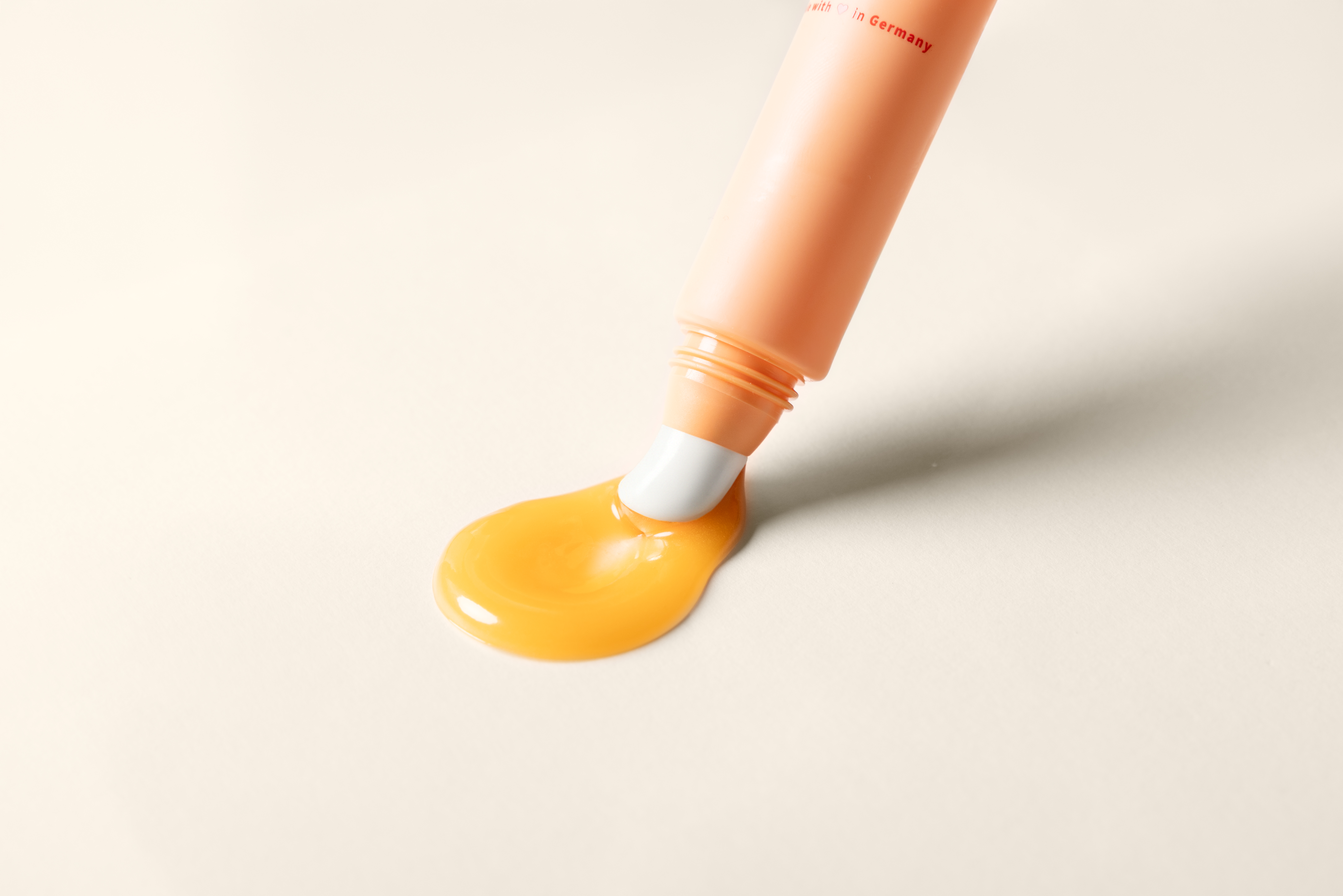 Nahaufnahme des Beyer & Söhne Dayshade Lip Balm SPF 50+ mit weißer Keramik Applikatorspitze, aus der goldener Balsam fließt