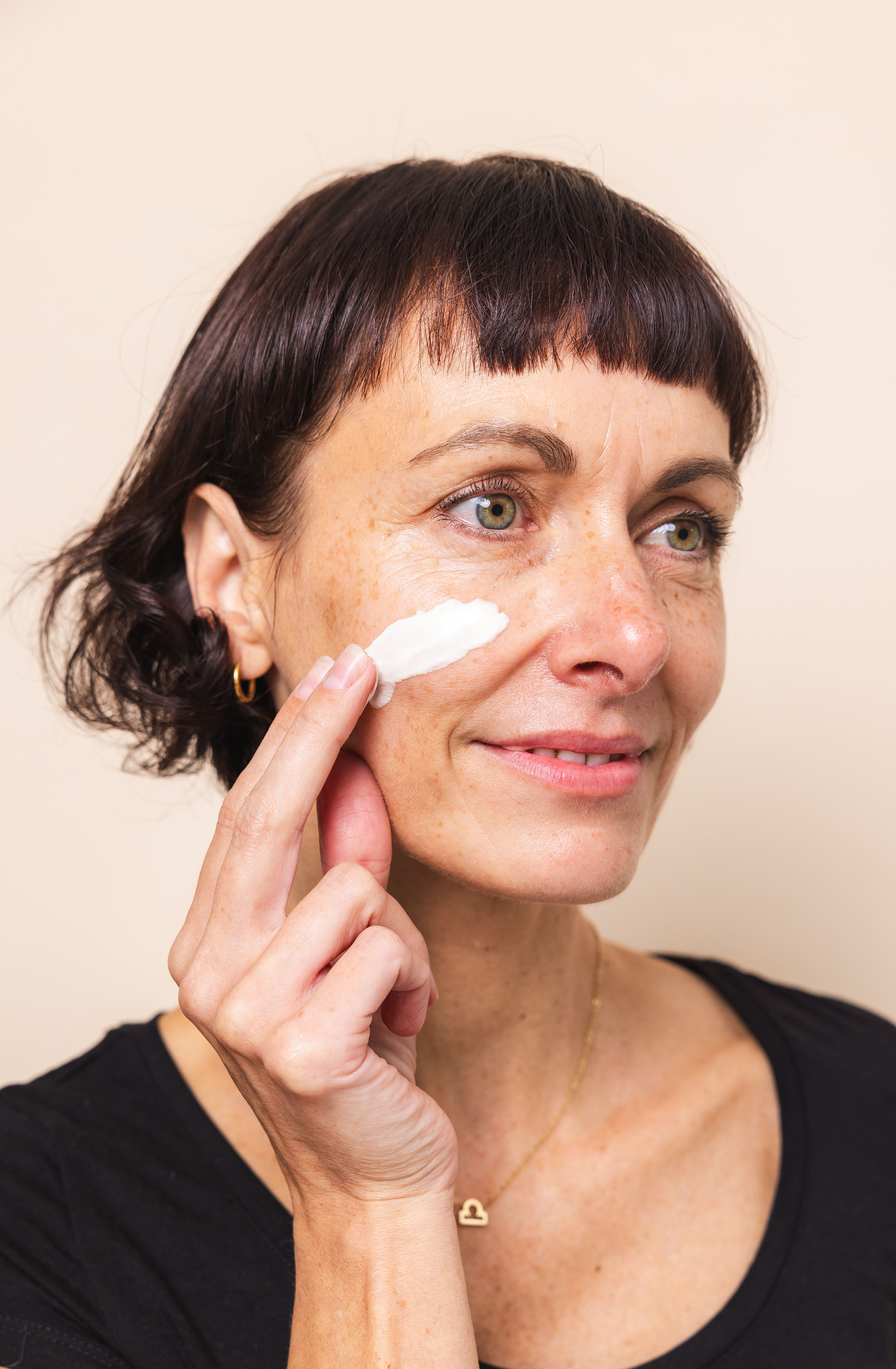 Frau, die sich mit der Hand Hautcreme auf das Gesicht auftrÀgt