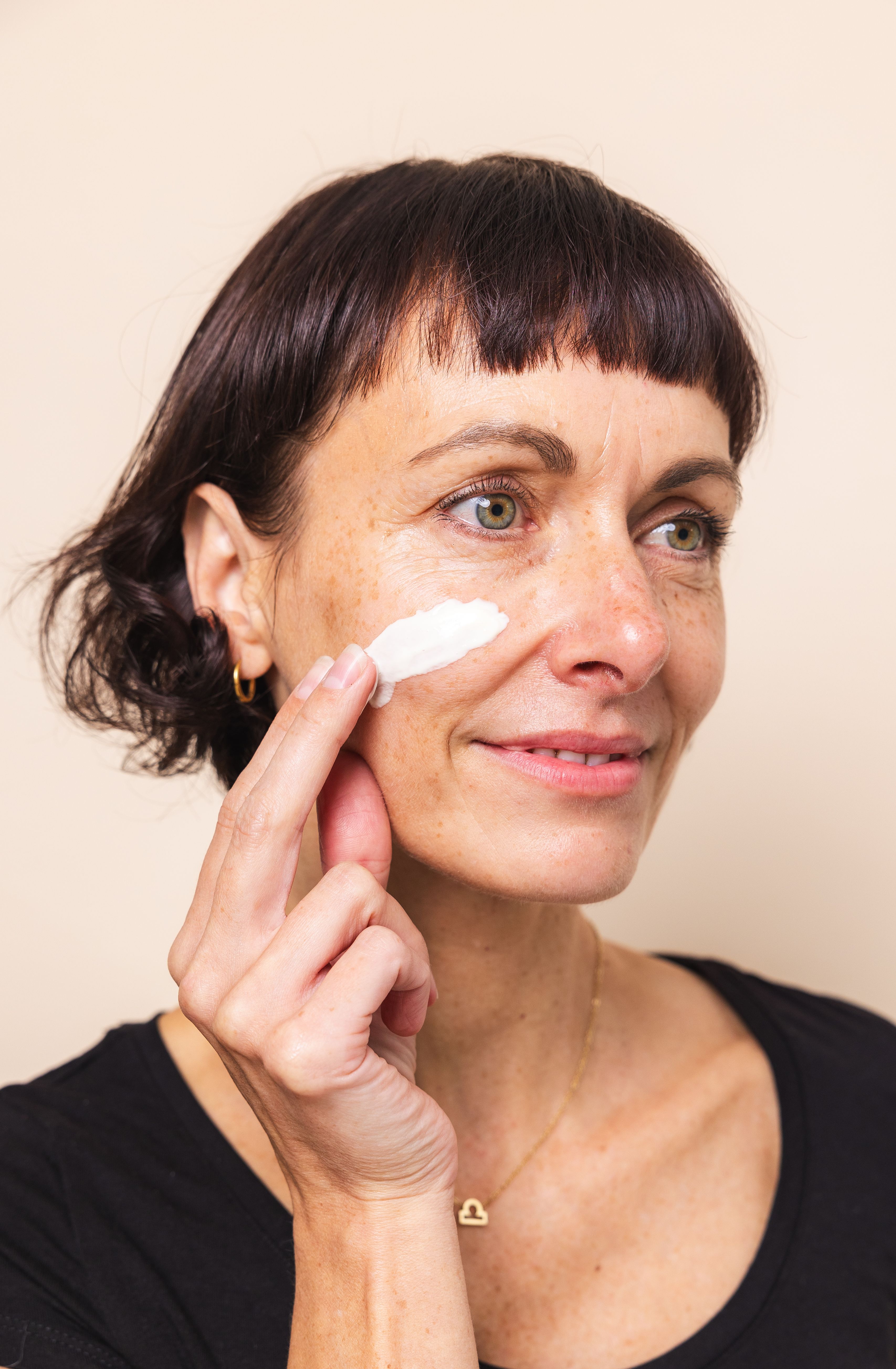 Frau, die sich mit der Hand Hautcreme auf das Gesicht aufträgt