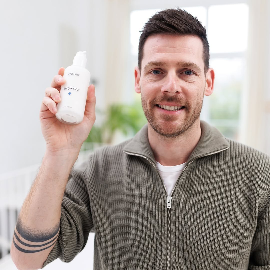 Lächelnder Mann mit Bodylotion in der Hand