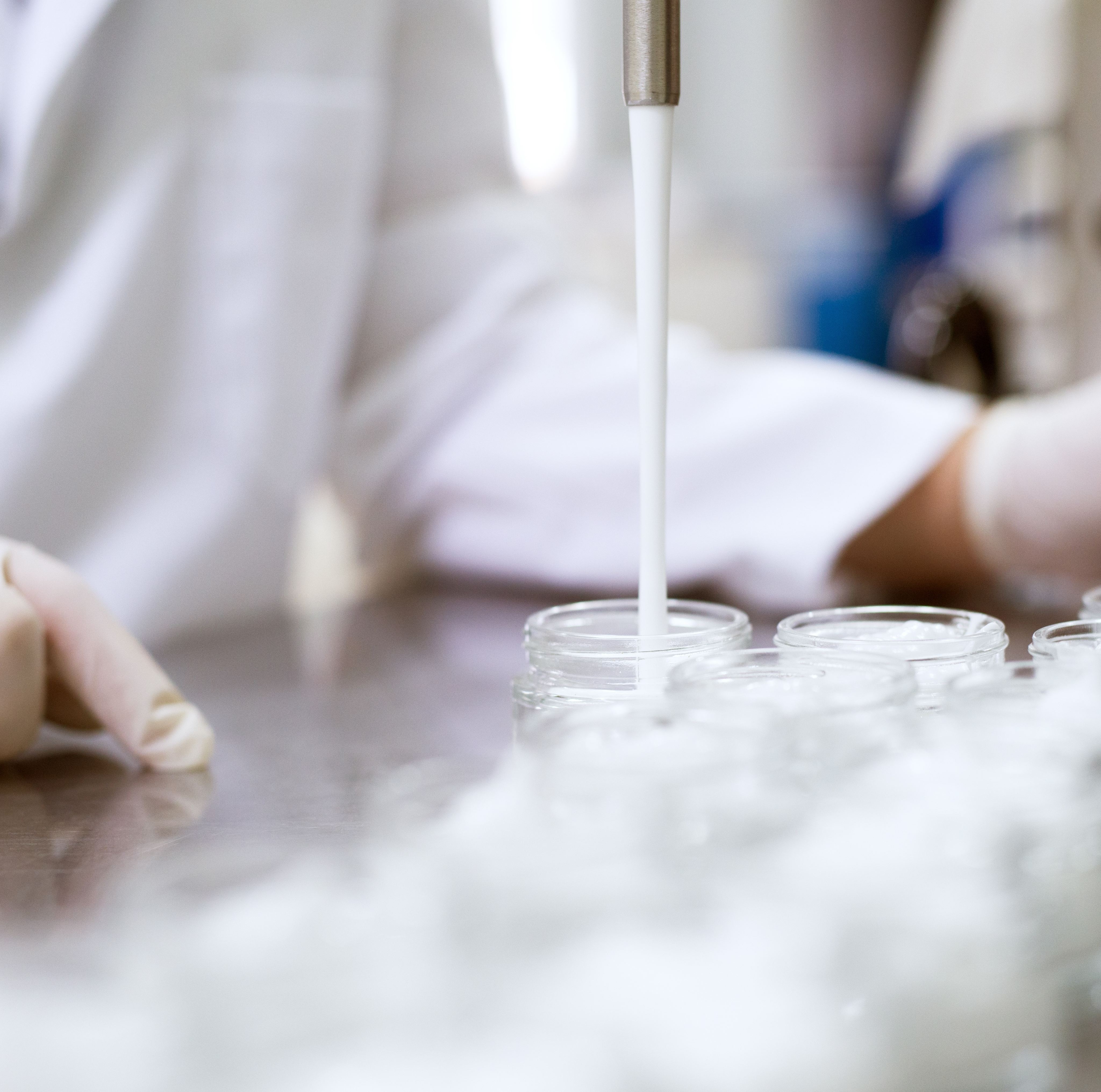Abfüllung von Hautpflege in Deutschland. Eine weiße Pflegeformulierung wird unter hygienischen Bedingungen in Behälter gefüllt. 