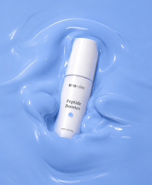 Peptide Booster von Beyer & Söhne in minimalistisch edler weißer Flasche, umgeben von glänzender blauer Textur, die durch die Kupferpeptide ihre Farbe bekommt