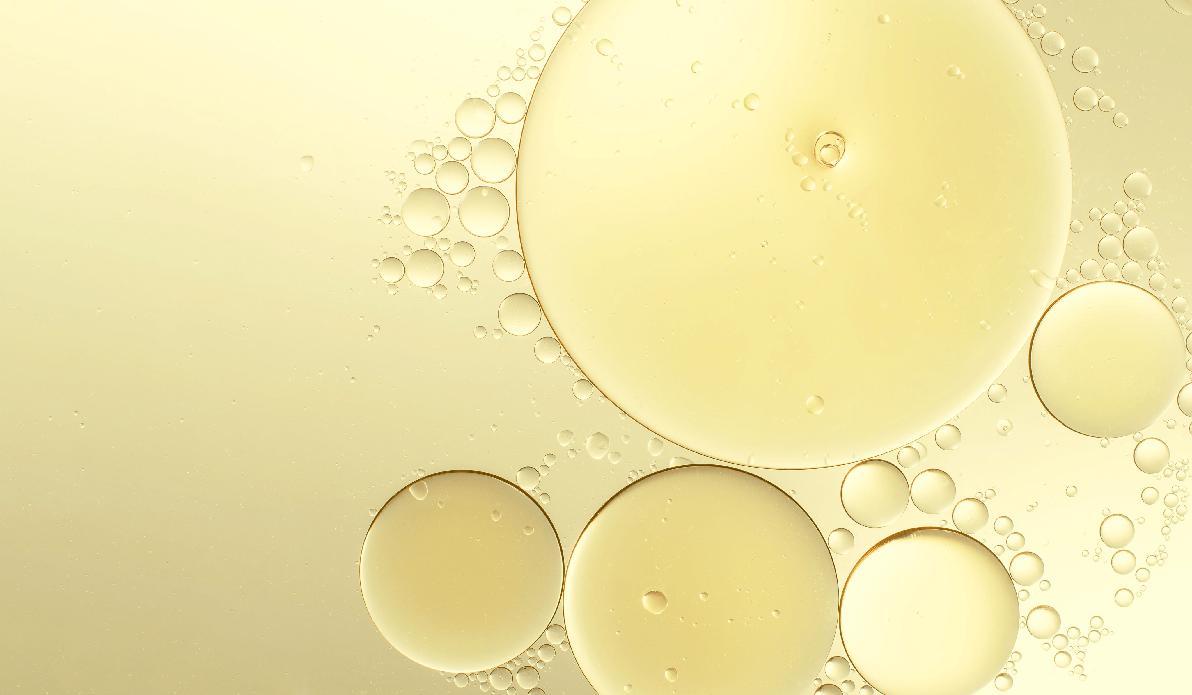 Gold-gelbe Flüssigkeit mit runden Strukturen, Symbolbild für liposomal verkapseltes Retinal in Hautpflege. Für stabile, sanfte und wirksame Abgabe des Wirkstoffs.