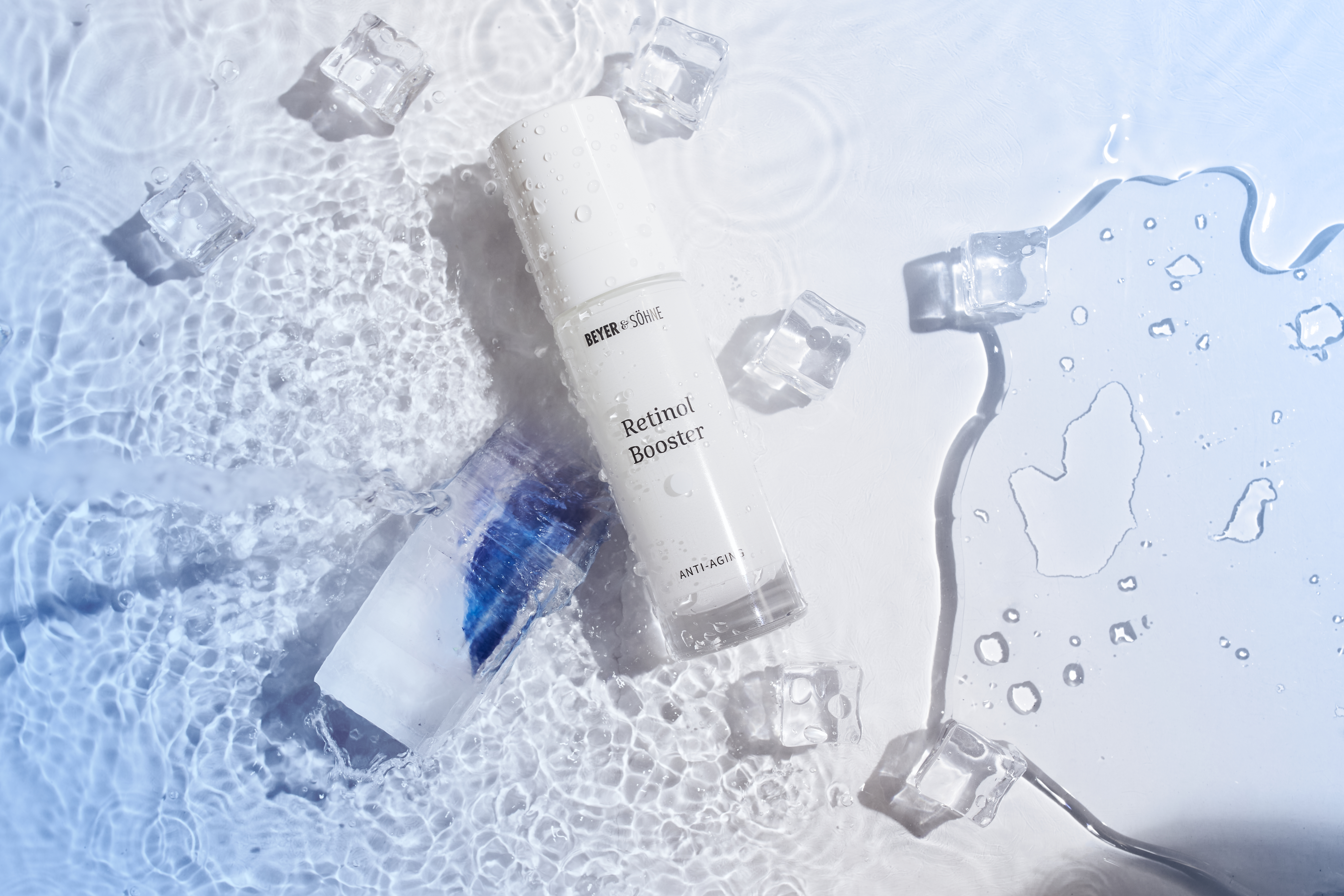 Retinol Booster von Beyer & Söhne zwischen Eiswürfeln auf einer wässrigen Oberfläche