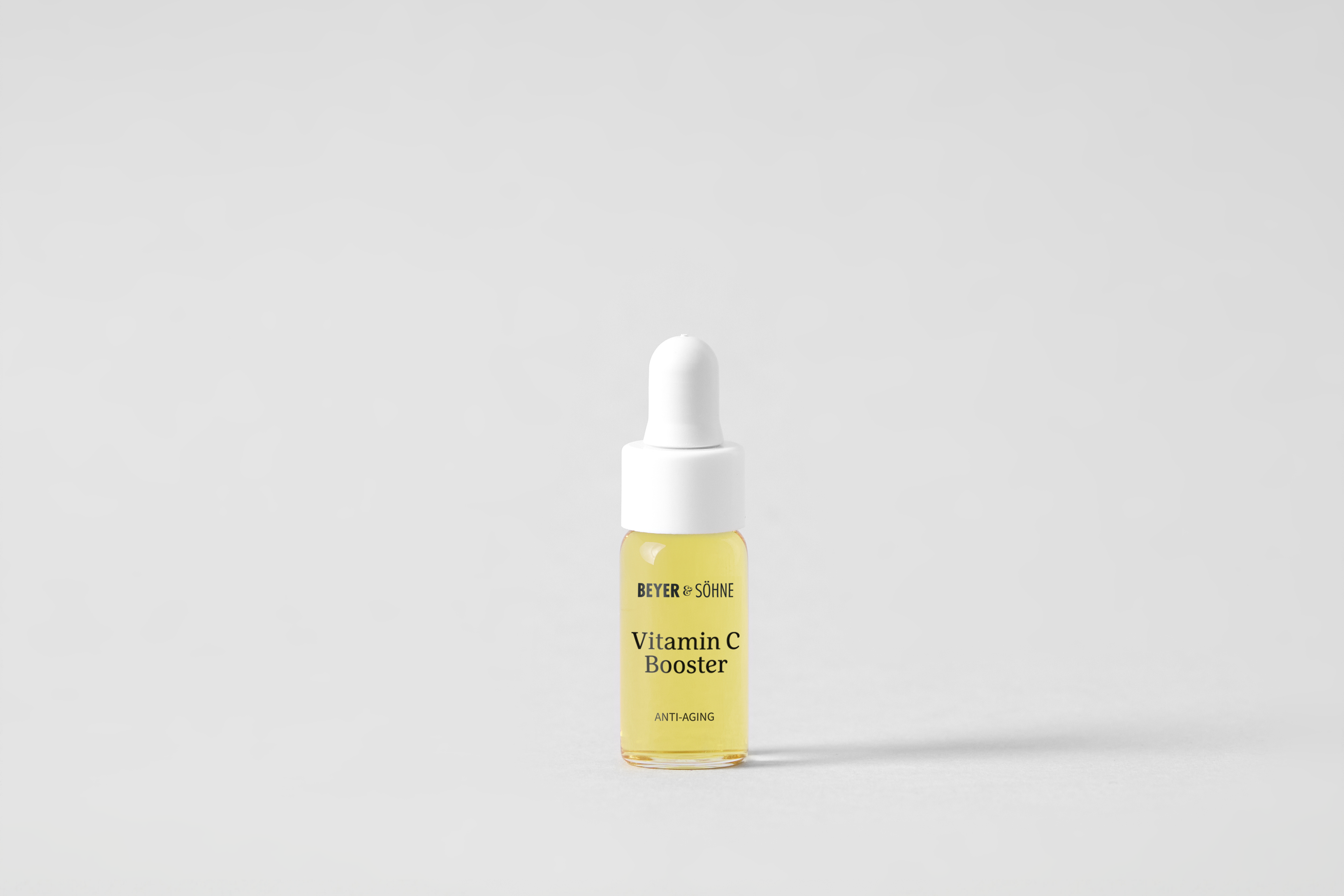 Vitamin C Booster von Beyer & Söhne in 4 ml Testgröße. Minimalistisches Design mit weißem Pipettenverschluss und goldgelber Serumfarbe. Hochdosiertes Anti-Aging-Serum für strahlende Haut, ideal zum Ausprobieren oder für unterwegs.