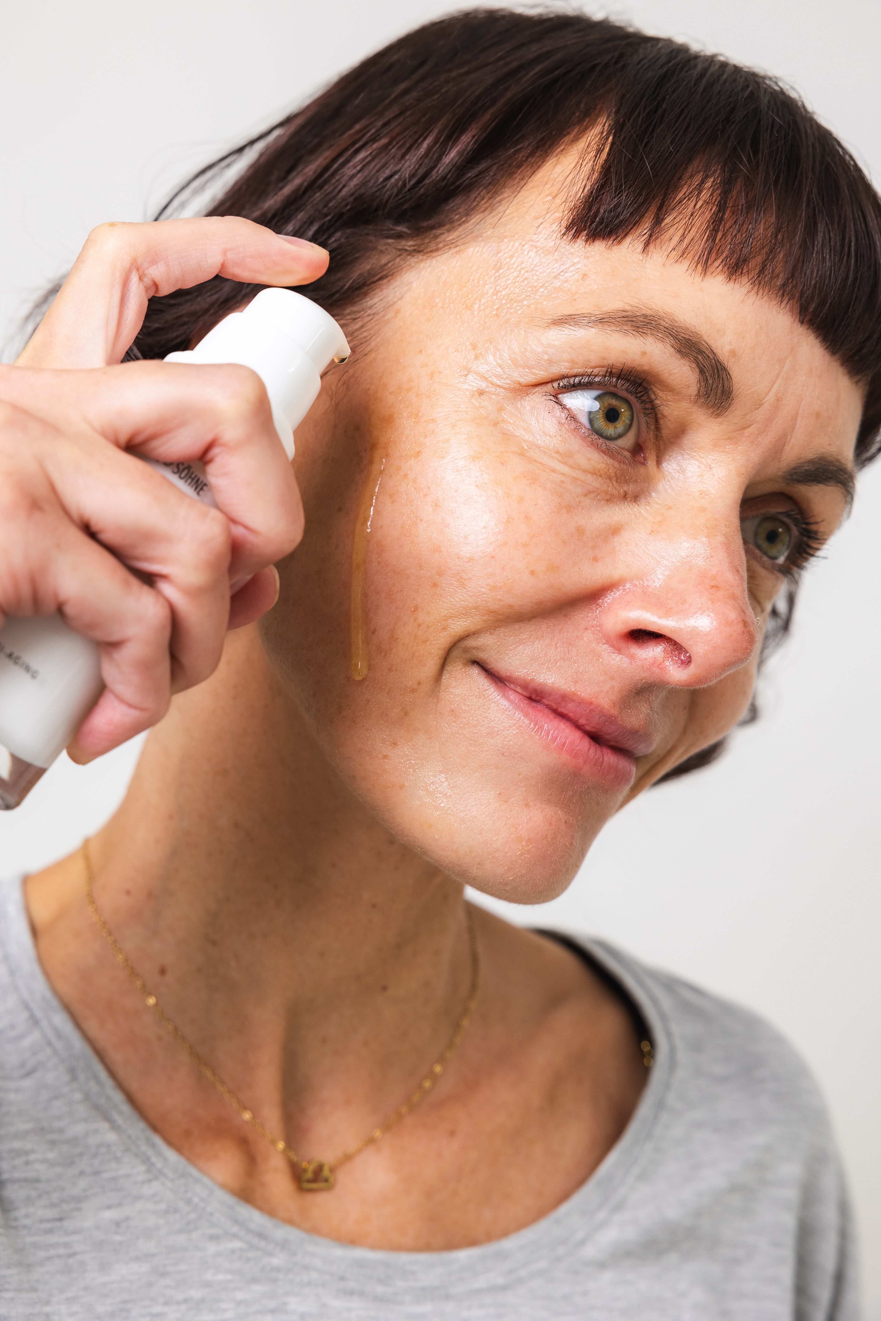 Frau trägt wenige Tropfen Vitamin C Booster auf