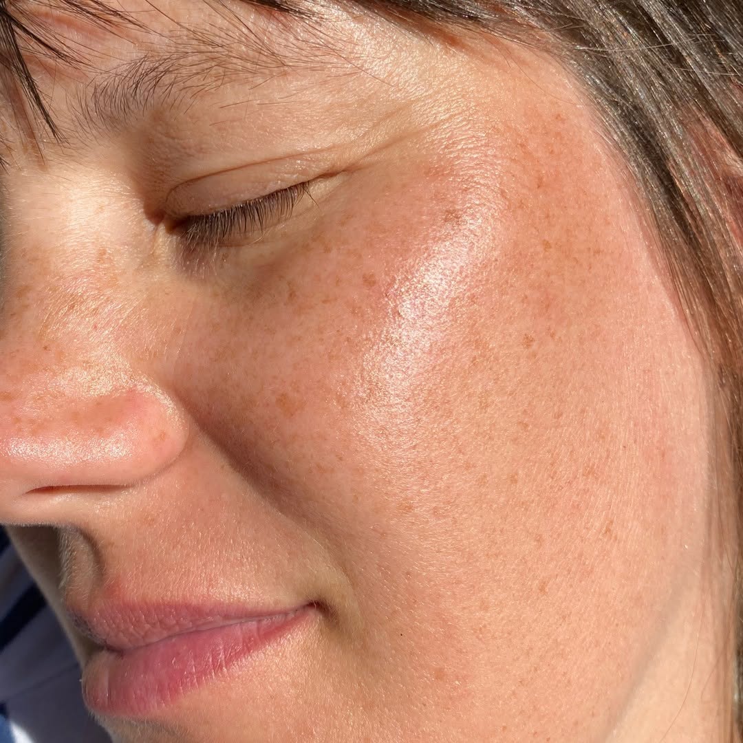 Nahaufnahme einer Frau mit geschlossenen Augen mit feiner, glänzender Haut